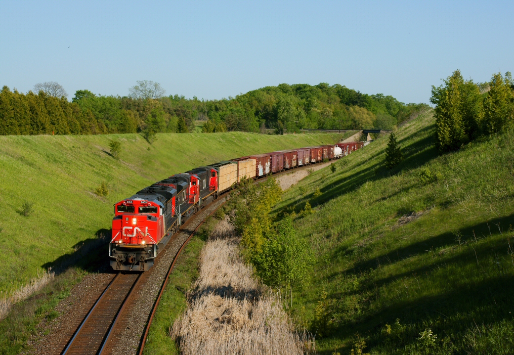 The sounds of 3 straining EMD 16-710 prime mover\'s can be heard for miles away, 2 SD70M-2\'s and a 75I are seen doing the uphill battle with gravity and heavy tonnage.