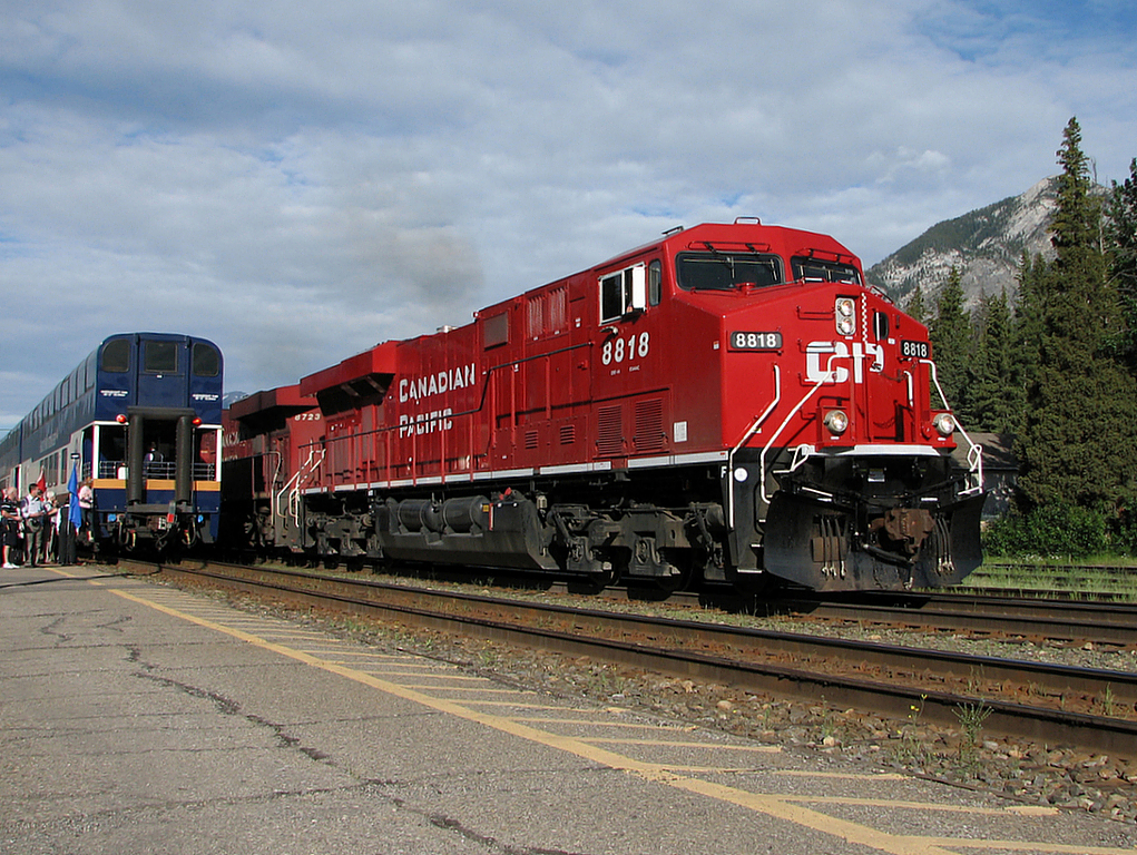 A empty grain train passes the westbound Rock Mountaineer as it loads passengers at Banff.