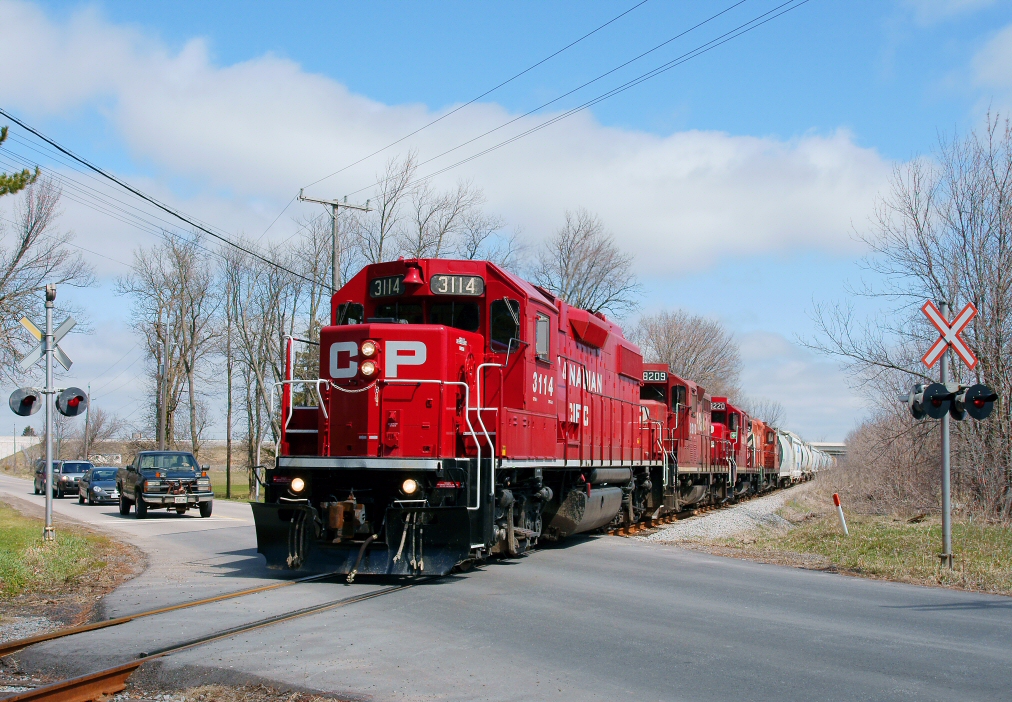 A collage of different painted geep\'s lead this westbound tonnage train through the 10th Line grade crossing to Agincourt Yard.