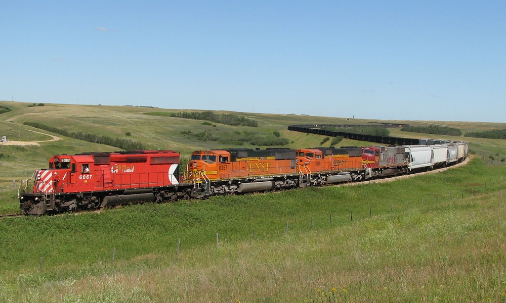 CP 878 or BNSF C-SCMMIB with 6067 and BNSF run-through power lead a 156 car coal train bound for Brandon snakes through the valley at Oxbow Sk.
