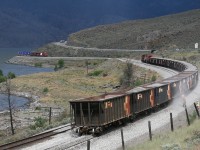 Work 5952 dumps ballast on the new track at Savona while Olympic GEVO 8866 skirts the shores of Kamloops Lake