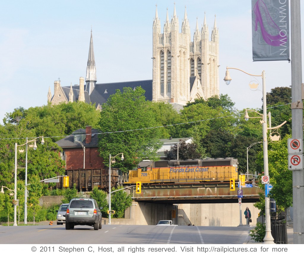 Far from home rails, Florida East Coast #709 is trailing Goderich and Exeter #432 through Guelph, Ontario past the iconic Church of our Lady, Guelph\'s tallest structure situated atop the highest point in town.