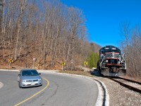 A locomotive and a car meet at a sharp hairpin curve in the road, both technological wonders from different frames in time, both built in Canada, the Japanese designed Civic built in Alliston, Ontario and the American designed ex CN GP9RM built in London, Ontario. With 5 cars to interchange to the CPR at Streetsville, the southbound twice a week train from Orangeville is seen here passing Forks of the Credit. 