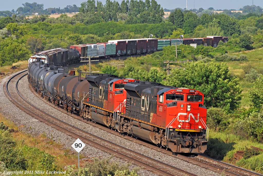 A pair of \'line backers\', CN 8866 and 8898 lead 369\'s train through the curve at Bowmanville. 1736hrs.