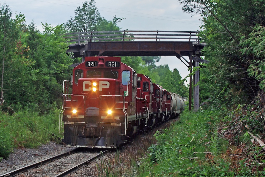 8211 heads up todays T07 along with 3114 3045 3133 with a load of 31 cars.Heading deep into the woods at Tapley Ontario.