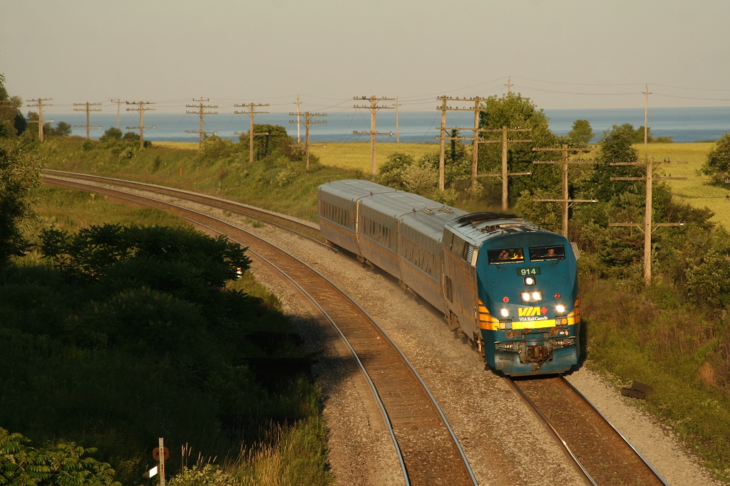 VIA 914 west cruises into the sunset with Lake Ontario in the background.