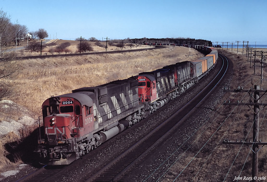A clutch of MLW M-630s rounds the curve at Lovekin (east of CN Clarke) with a container train in late winter 1986.