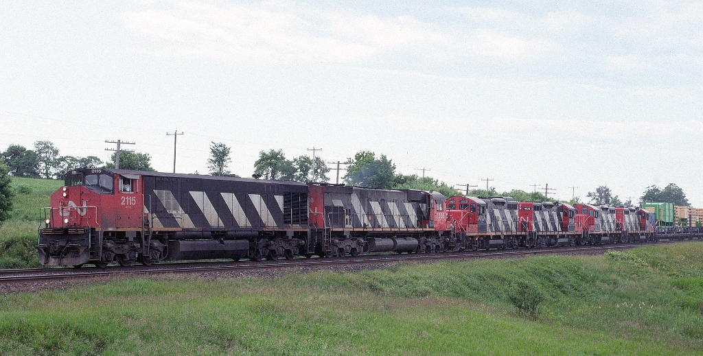 CN HR-616 2115 leads M-636 2303 and a brace of GP-9s east at Nichols Road, Newtonville with train 318.