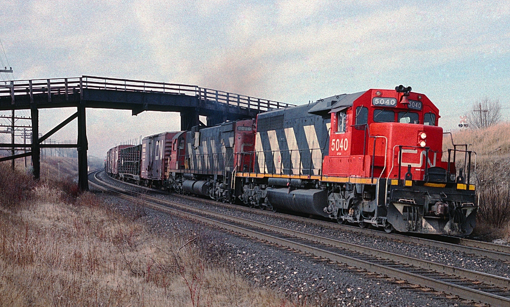 An SD40 and an M-630 head up train 390 passing under the bridge at Lovekin, between Clarke and Newtonville on the Kingston sub in March 1990