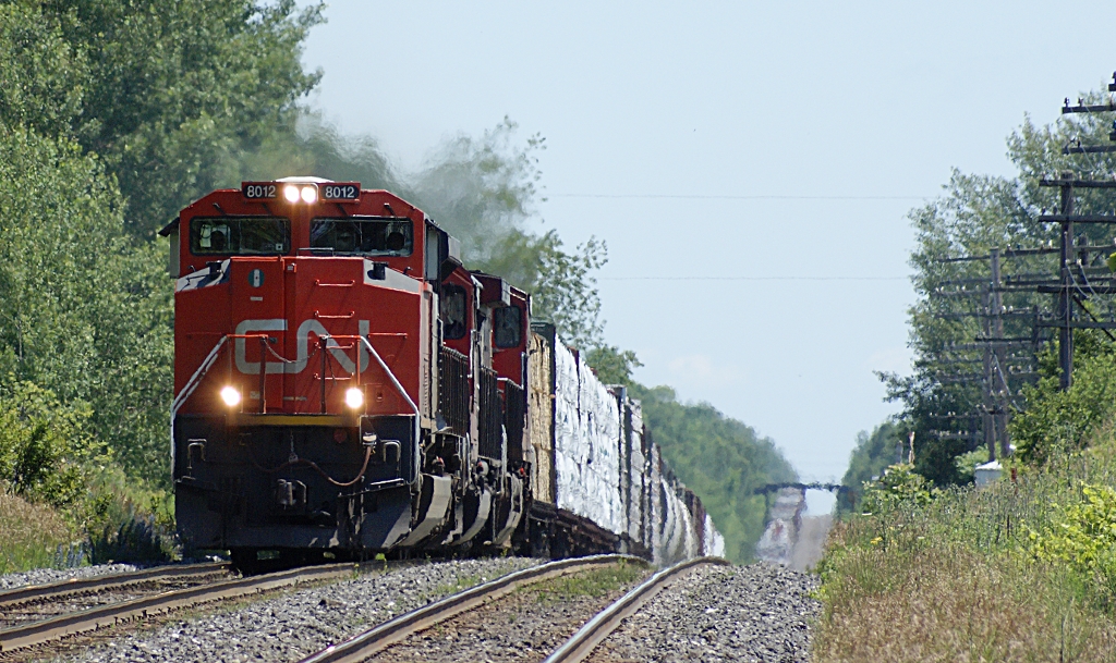 SD70M-2 8012 emerges from the telephoto-exagerated dip on the Kingston sub between Brighton and Colborne with train 369. This part of the Kingston sub is known as \"the dangers.\" Its undulating profile has led to many a pulled drawbar or broken knuckle.