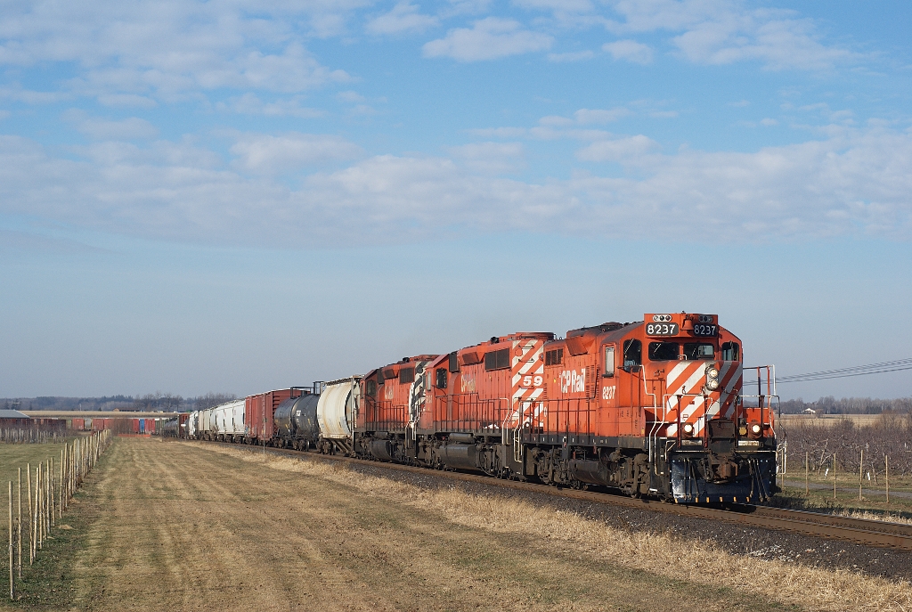 GP-9 8237 leads a couple of SD40-2s on an eastbound drag through the orchards at Concession Street, halfway between Bowmanville and Newcastle in December 2006.