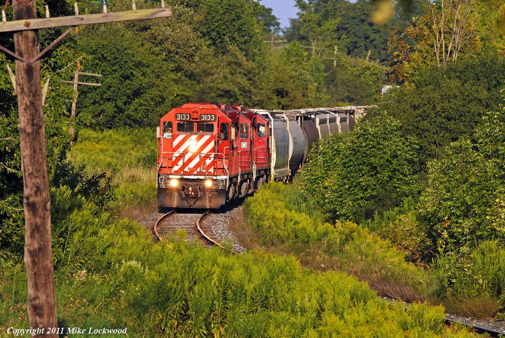 I\'ve been wanting to scratch this shot off my to-do list since 2008. Done, thanks to the Friday afternoon departure of T07. The westbound Havelock negotiates the S-curve west of town, and at one time would have passed under the one time Whitby, Port Perry and Lindsay Railway, long abandoned through here. CP 3133, 3045, and 3114, 36 cars. 1857hrs