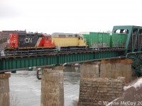 Leased shiny CN7079 and new-to-NBSR 110 cross the Reversing Falls Bridge westbound with a transfer from Island Yard.