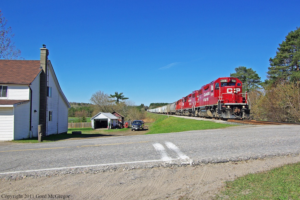 A man out doing some yard work pauses to watch T08 pass by with 40 cars on Mothers Day 2011
