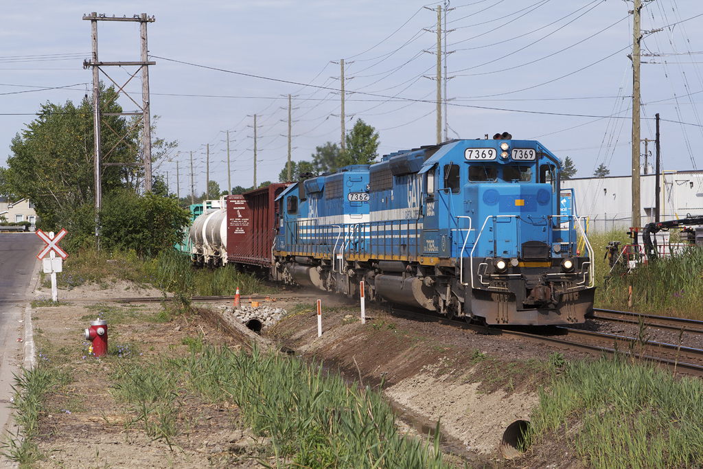 GEXR 432 (K43231 XX to CN), a GEXR transfer of traffic from Stratford-Kitchener to CN Mac Yard pounds the diamond at Brampton on this hot summer morning.