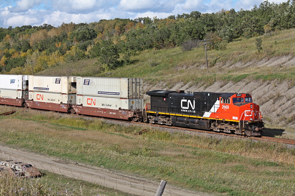 A clean CN 2669 is the rear dpu on Q111 at Miniota as the long intermodal descends down to the valley on a fall afternoon.