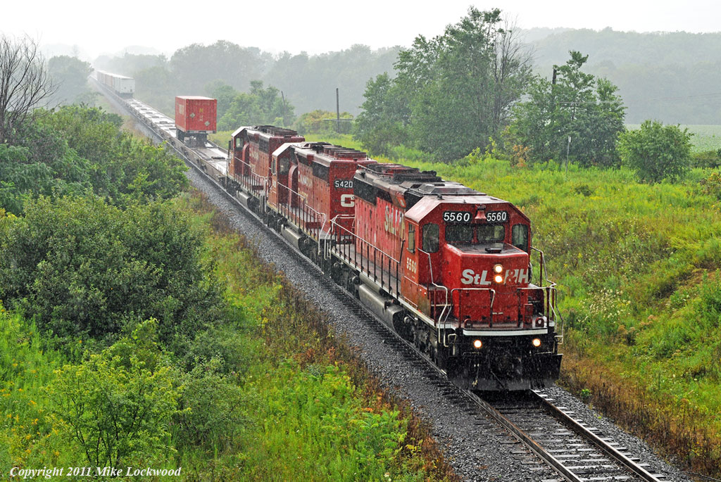 A few notable SD40-2\'s power the eXpressway east about a mile west of the Port Hope siding as the rain eases. STLH 5560 leads CP 5420 and 5730. 1509hrs.