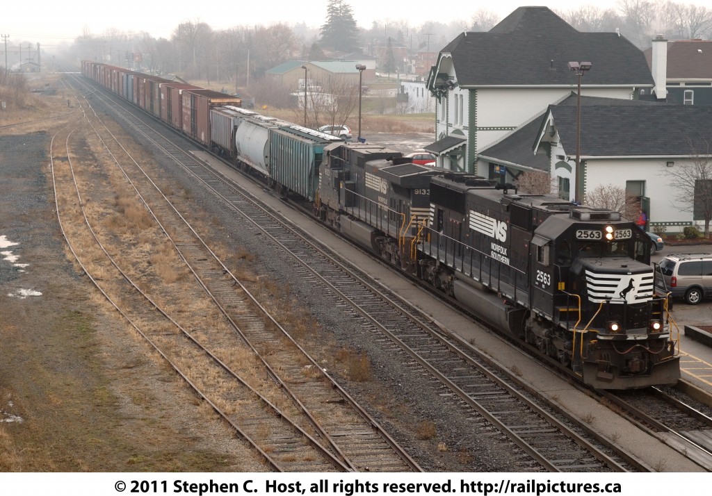 The now discontinued NS train 327 is passing the Woodstock VIA Station, where moments earlier VIA #73 let passengers off on the morning run to Windsor. The NS train contains hoppers of Grain for customers on the STER (Trillium) line as well as parts for the Ford plant near St. Thomas.
