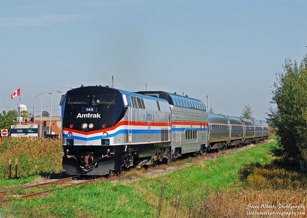 The annual fall foliage dome car addition to the Amtrak Adirondack train was complimented this year by its arrival in the Phase III paint. Amtrak also assigned the Phase III P42DC 145 to the Adirondack service to be mated with the dome car runs. On September 27, the Amtrak Adirondack train 68 is passing the Canadian Customs station - the train is still in Canada at this point, the photographer is in the US!. Many more photos at http://steelwheelsphotography.com.