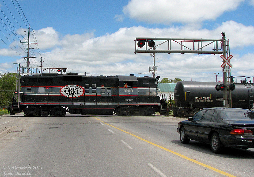 Tying up traffic on Townline Road has been a tradition for years, and Cando Contracting GP9 1000 keeps it alive as she switches the OBRY\'s Orangeville Yard after completing a run to Streetsville and back. Once her train is assembled, she will make her way to the north end of Orangeville to service some customers before calling it a day.