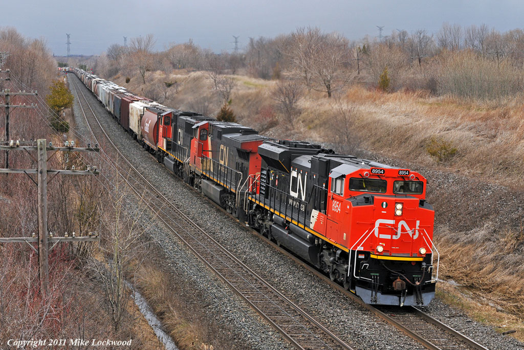 Racing ahead of a mid April snow squall, CN 8954, IC 2720, and CN 5701 lead grain train 874 through Lovekin. 1435hrs.