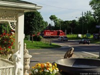 Statues and cars alike wait as 8211 a GP9 leads T07 in historic Myrtle Station on Canada Day.