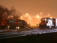 Power for CN 550 and 547 are illuminated by the headlight of an approaching train, on a foggy December evening