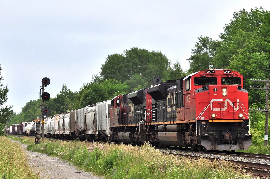 IIt is a cloudy humid day at CN Newtonville as CN#369 (with 8898 - 8832) rolls slowly west over the Newtonville crossover awaiting clearance from the roadforeman working at Clarke