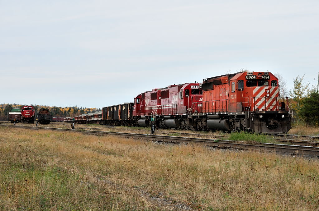 Rare appearances, in unusal places. In the small \"north yard\" at Ignace, Ontario, a rare scene takes place. Fresh in from the Dyment Pit, the \"rock train\" numbered 9965-09 sits in track six with SOO SD60\'s 6046 + 6043 with CP 6024 while down in track 2 SOO SD60 6045 sits solo with an apparent b/o trainline or hosebag. It will be lifted on the nights Paper train.