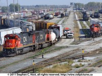CN 2129 is leading CN 509 who is building their train @ Sarnia, with CN 393 heading to Port Huron beside it on the left. To the right is a CN remote control yard job performing switching duties in what is known as Sarnia \"A\" yard. 