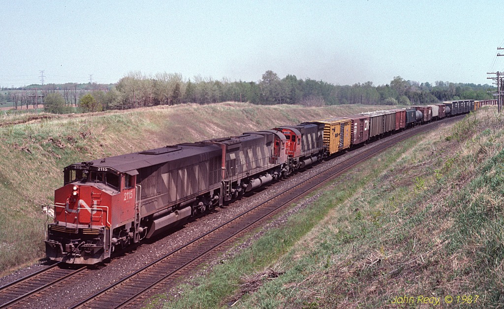 HR-616 2115 leads two MLW M-636s west at Nichols Road, Newtonville in June 1987. I\'m struck by how devoid of overgrowth the right of way seemed back then.