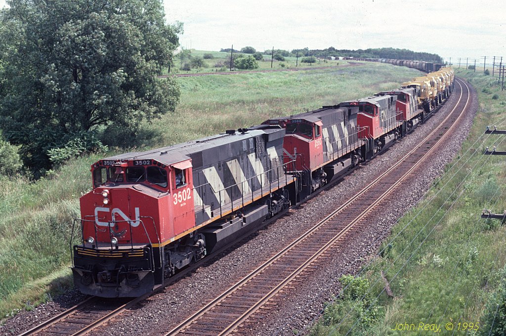 Four MLW M-420s drift down grade to towards Clarke and are about to pass under the Lakeshore Road bridge adjacent to CP\'s Lovekin siding in July 1995