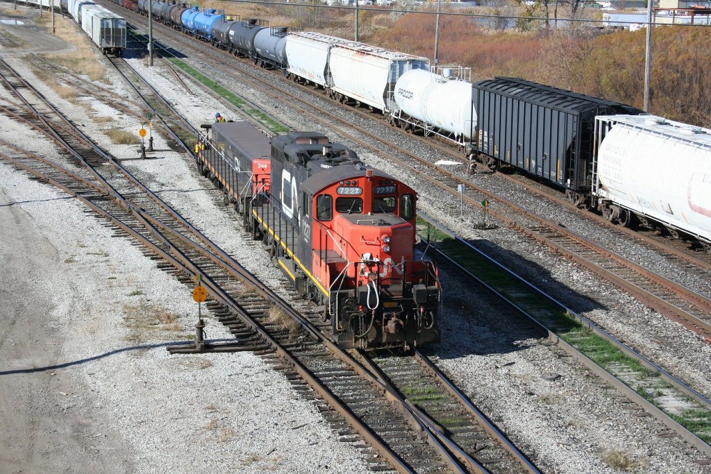 With CN 385 working on the main building its train in the \"A\" yard at Sarnia, a yard job works away at the never-ending task of sorting cars in the \"C\" yard which mostly supports the local industries in Sarnia.