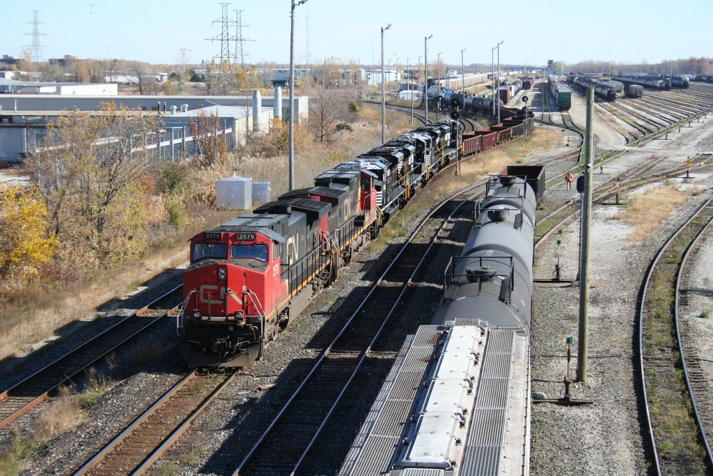 As a yard job works on a cut of cars on the adjacent lead, CN 385 begins its pull past the the US Customs inspection as it makes its move for the St Clair Tunnel and the crossing into the United States. In tow directly behind the power today is a quartet of shiny new SD70ACe locomotives for Norfolk Southern, fresh from the EMD factory in London.