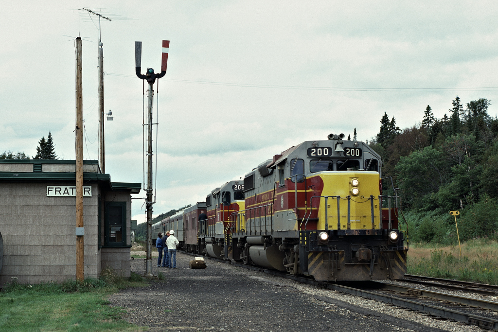 The train order board (signal) is set at clear (green) nevertheless the Algoma Central Railway Agent/Operator is busy selling passenger tickets on this warm September 1, 1984 as Algoma Central Railway train #2, powered by  two three year new GP-38-2\'s, pulls into Frater, Ontario. Kodak Kodachrome ASA64 Diapositive transported by a Nikon F2. Photographer S. Danko.