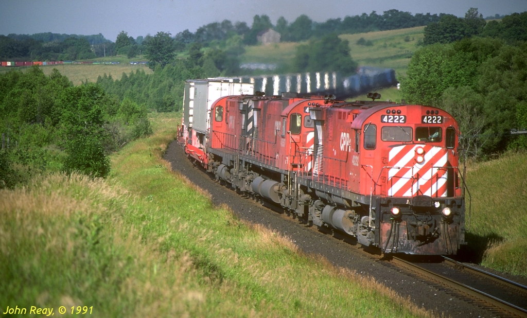 CP C-424 4222 leads an all MLW lash-up through the Newtonville S-curve approaching the wooden bridge at Nichols Road with an eastbound container train in July 1991