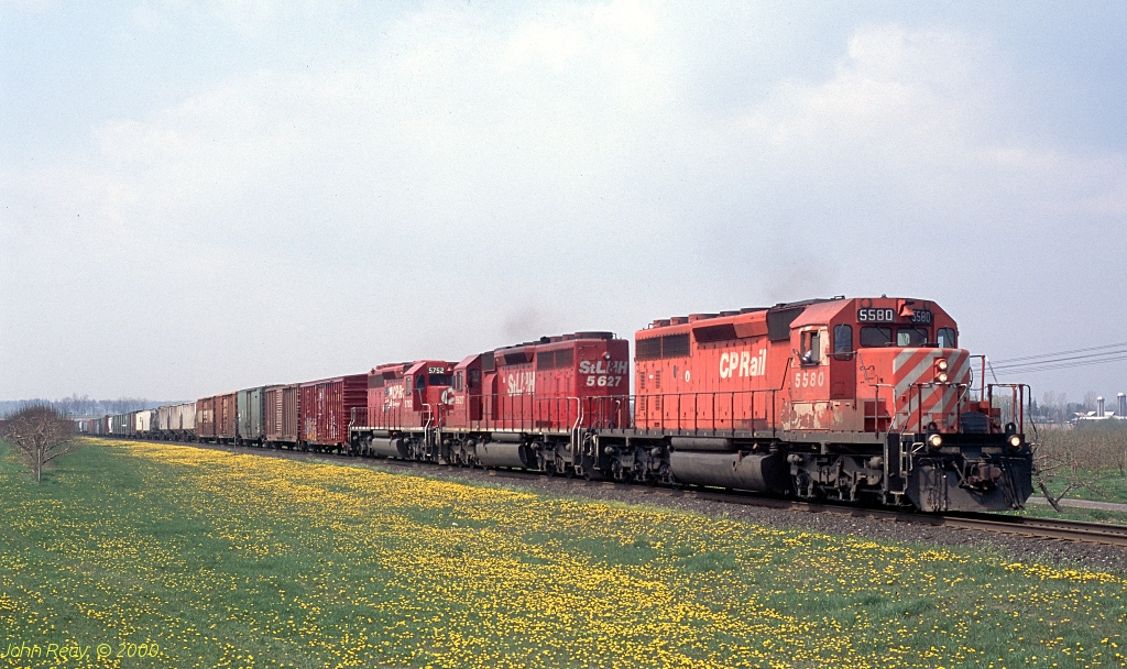 SD40-2s in three different paint schemes lead an eastbound through the dandelions at Concession Street between Bowmanville and Newcastle, ON
