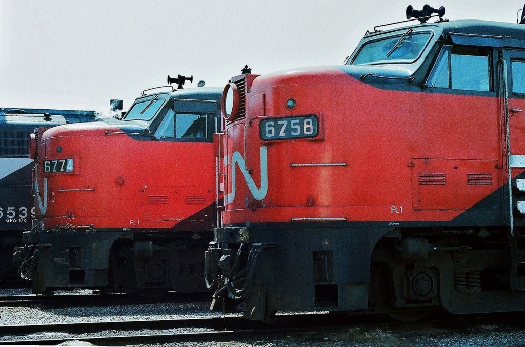 Cab Units. A study in a classic \'flat nose\' cab design, initially crafted circa 1946 with the ALCO PA design, here is MLW built (circa 1956) FPA-2u  CN 6758  and  FPA-4 CN 6774 (circa 1958). Both are now Via Rail property and await next assignment at the CN Spadina Motive Power Shop. The units will be repainted by CN into Via livery  before summer\'s end.  June 1977 Kodak Kodacolor II ASA100  negative transported by a Nikon Nikkormat EL. Photographer S. Danko.
