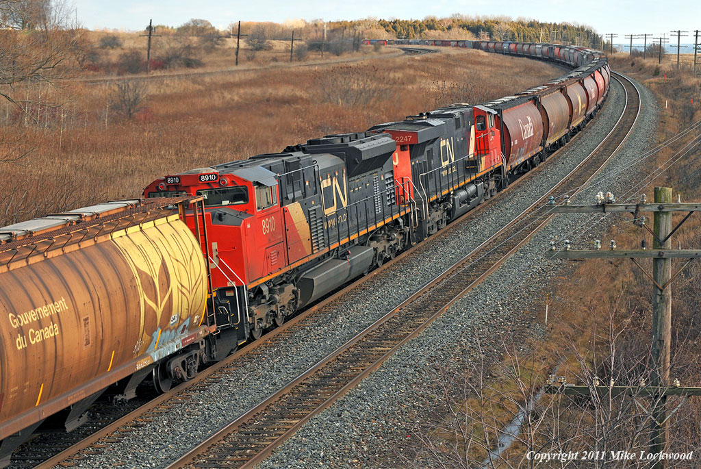 Grain train 874\'s mid train DPU, consisting of CN 2247 and 8910, lend their support to the headend power (CN 2320 and 5768) in moving the 155 car, 22000 tonne train east. 1433hrs.