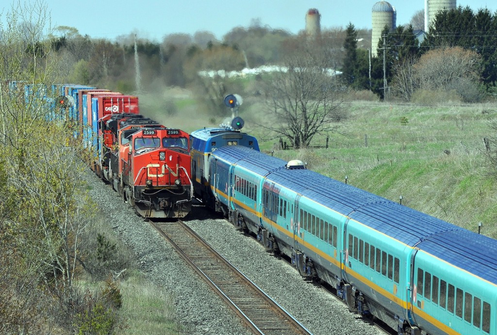 Following a west bound freight a late Via 53 with 904 and Renaissance equipment is further slowed with a clear to medium signal at CN Kingston subdivision mile 280 as an eastbound CN double stack blasts by with 2599 – 5712 – 8916 (Dash9-44CW / SD75I / SD70M-2). May 10, 2011 Image by S. Danko.