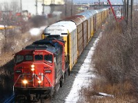 CN 5558 and 9411 haul a long #271 of solid autoracks through (old) Peel, passing MofW employees working at the Kennedy Road bridge. In the distance is Highway 410, and the various factories of the Brampton/Peel Village industrial area. This section of single track between Peel and Brampton East has since been triple tracked as part of the GO Georgetown line expansion.