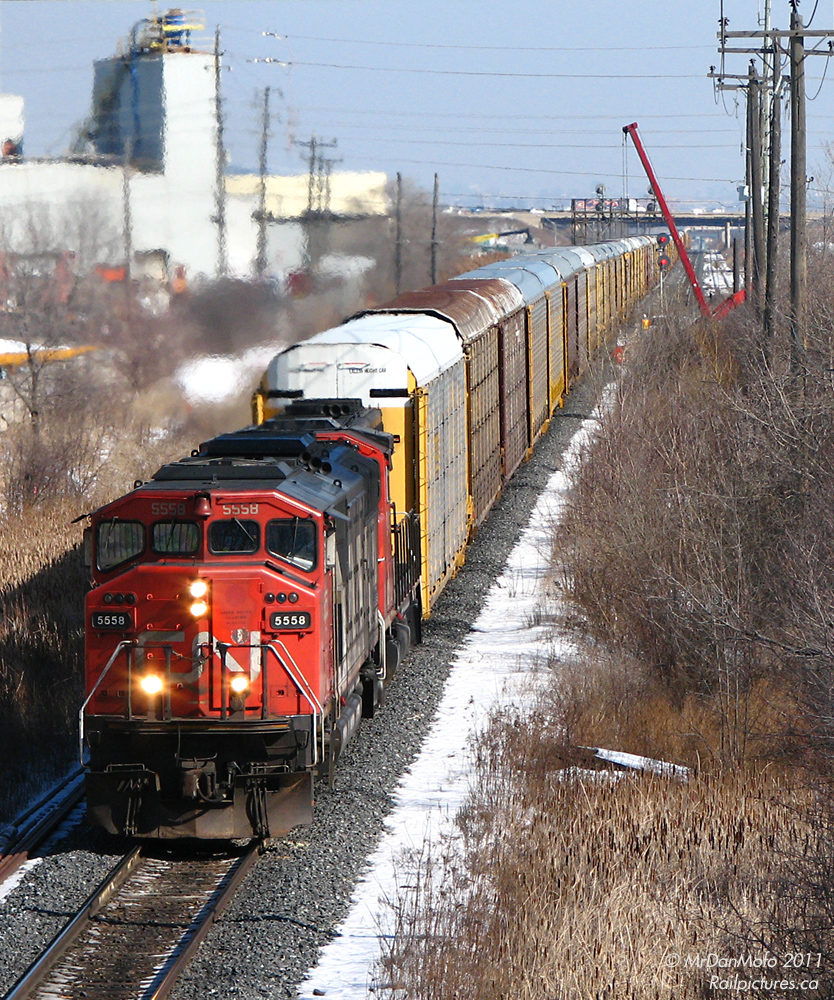 CN 5558 and 9411 haul a long #271 with solid autoracks through (old) Peel, passing MofW employees working at the Kennedy Road bridge. This section of single track between Peel and Brampton East has since been triple tracked as part of the GO Georgetown line expansion.
