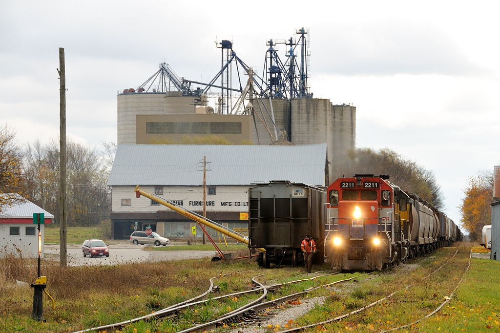 It\'s train time in Clinton as the conductor off GEXR 433 heads to knock the derail off to set one grain hopper in the back track. This is today\'s local for the Exeter Sub, once back on their train they will head south at Clinton Jct to spend a couple hours switching Hensall then down to the end of track at Centralia to spot the P&H elevator and get relieved. Power this day was RLK GP35 and LLPX GP38-2 2236.