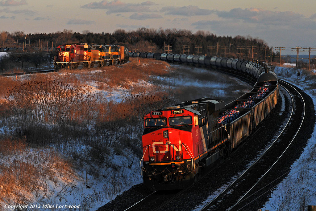 No race here as CN 305, behind CN 2295 and DPU 8004, handily whips past CP 643 at Lovekin. 643, behind CP 5995, CITX 2790, ICE 6404, and ICE 6456 is slowly pulling through the siding as CP 130 (out of view with CP 5746, CITX 2797, and CP 5923) holds the main. Eight minutes earlier, CN 372 has roared past; four freights in under ten minutes. A long day of foaming and driving began at Lovekin in the morning as I chased a pair of SD9043MAC\'s on 3rd 234 as far east as Roblindale. Yes, they are that rare on the Belleville Sub. However, I quickly lost interest in the SD90\'s as 643\'s colourful lash-up exited Roblindale siding after meeting 3rd 234. One more shot of 643 in the glow of dusk at Bowmanville topped off what was a pretty good day. 1659hrs.