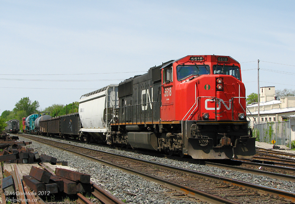 After a meet with VIA #85, now sitting at Georgetown station in the background,  CN dimensional extra X388 sits west of the Credit River bridge awaiting a light. The train consists of CN SD70i 5618, a number of idler cars for braking, Schnabel car KWUX 301 with a large Siemens generator from North Carolina, and ex-CP caboose KRL 075. Due to the large nature of the \"D9R\" dimensional load rating, this train was limited to maxium 35mph, subjected to restricted meets, and could only travel during the day.