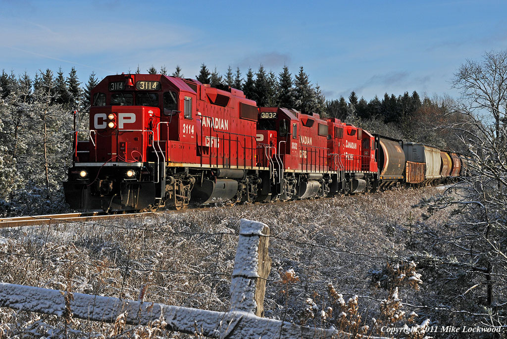Westbount T07 approaches the Darlington - Manvers Town Line road with 22 cars behind CP 3114, 3032, and 3111. 0955.