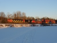 CN Q10721 21 - CN 2405 North hammers across Torpitt rd. as the last 3 minutes of daylight creeps across the ice before burying the right of way in shadows.