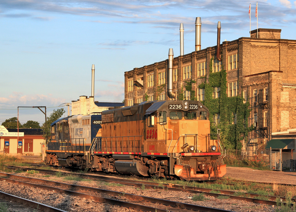 Just minutes after sunrise, LLPX 2236 and GEXR 4001 bathe in perfect light at Kitchener Station in front of an old furniture factory.