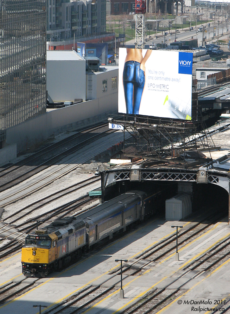 VIA #60 makes its timely 11:30am departure out of Union Station, amid the skyscrapers, condos, and the rather large billboard ads of downtown Toronto. In the background part of the ex-CPR John St. Roundhouse could be barely seen.