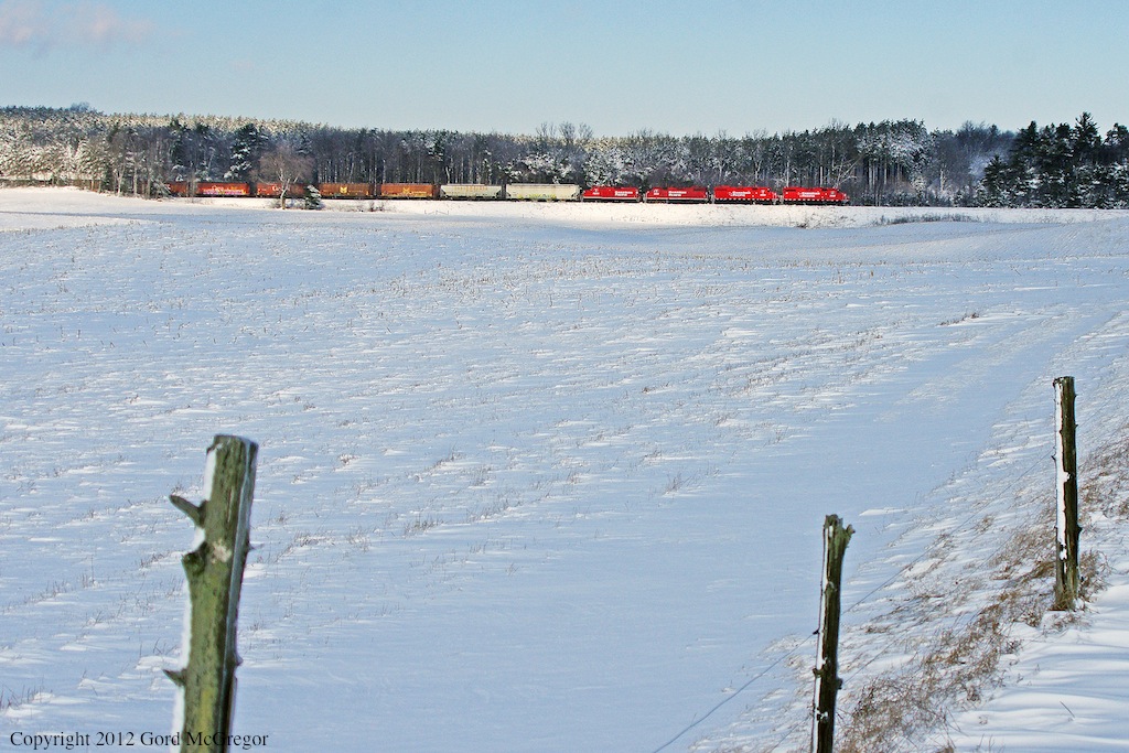 Rolling past the open fields and fresh snow near Burketon T08 with a matched consist and 5 grain cars on the head makes its passage.